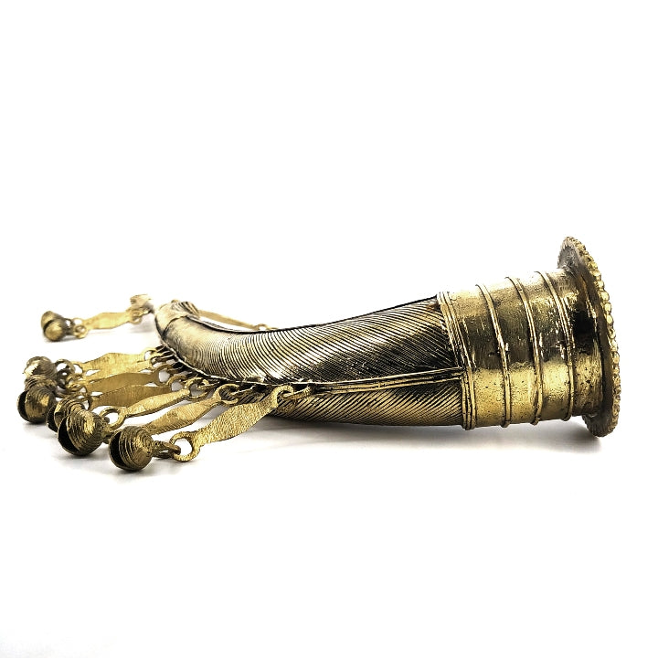 Side view of Dhokra brass trumpet featuring engraved patterns and hanging bells.
