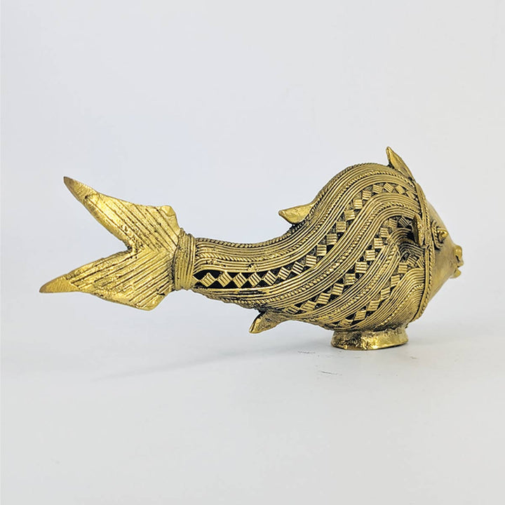 Close-up of intricate tribal patterns on brass fish figurine.