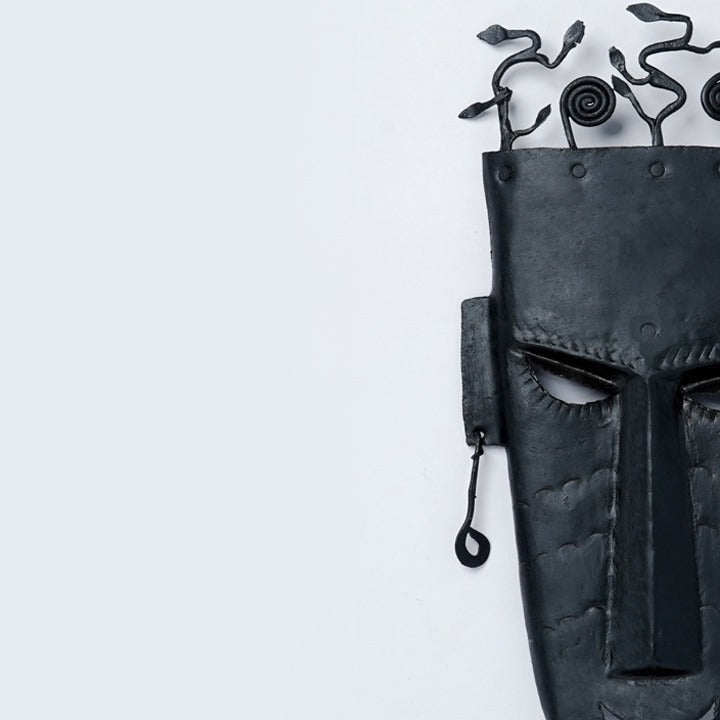 Close-up of Iron Sentinel wrought iron wall mask with bold tribal features