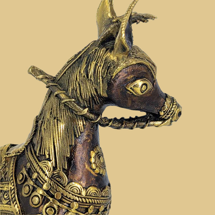 Close-up of intricate tribal engravings on brass horse figurine.